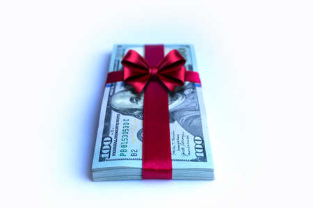 A bundle of one hundred dollar bills tied with a red ribbon close upの写真素材