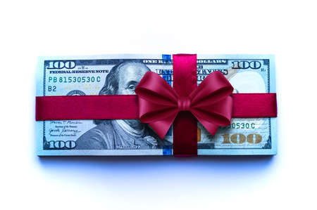 A bundle of one hundred dollar bills tied with a red ribbon close up