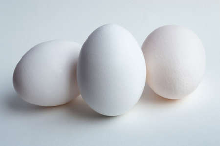 Three chicken eggs on a white background close up in detailの写真素材