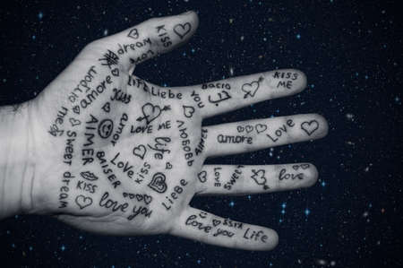 Male hand all painted with the word LOVE in different languages close upの写真素材
