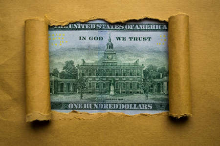 From under the torn paper you can see a 100 dollar bill close up
