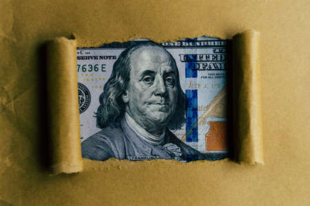 From under the torn paper you can see a 100 dollar bill close upの写真素材