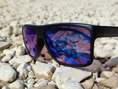 Sunglasses lie on sea stones close up in detail.の写真素材