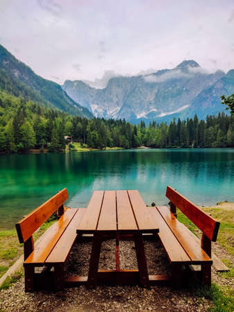 Bench on the shore of a mountain lake with a beautiful landscape during the day.の写真素材