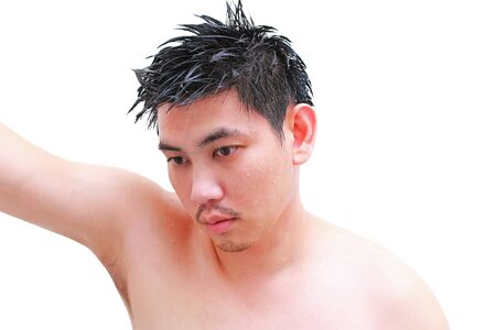 young man taking a shower and standing under flowing water in bathroom ,isolated on white backgroundの写真素材