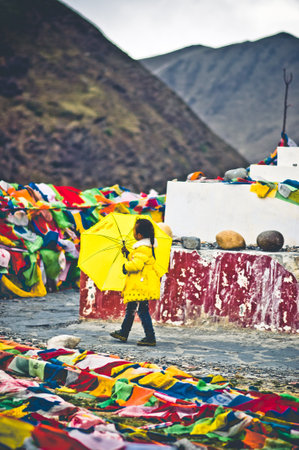 Tagong, China on 12th May 2015 - View on girl with yellow umbrella going arround tibetan stupaのeditorial素材
