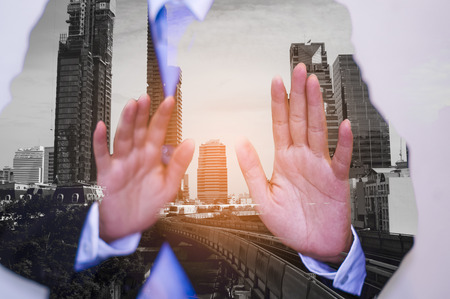 Double exposure businessman wearing a black suit, raising both hands, Background city landscape, Anti-corruption conceptの写真素材