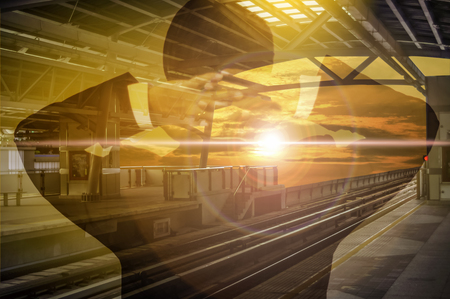 Businessman standing gazing out into  sky. On the sky train station,  is sunlight yellow evening sky background.の写真素材