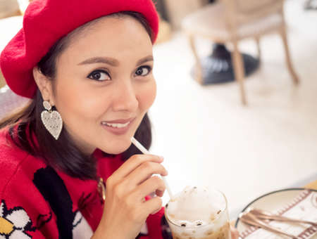 Female beautiful portrait smile fashion wear red is drinking eat coffee tea shop restuarant lifestyle merry christmas happy new year holiday vacation new normal after covid-19 corona virus diseaseの写真素材