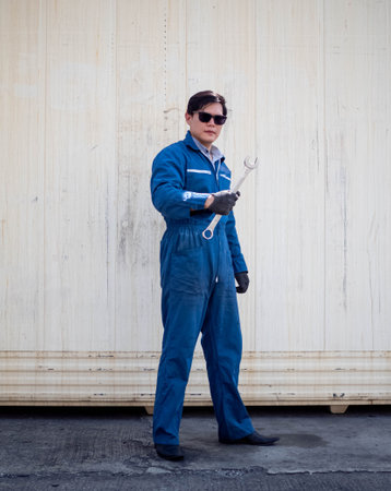 Male wear uniform glasses stand look at camera holding flick screwdriver technician engineer foreman supervisor industry container import export person people equipment service worの写真素材