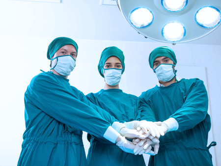 Hospital clinic emergency operation light room indoor doctor nurse staff assistance female male person woman man people touch hand teamwork group look at camera wear uniform mask gの写真素材