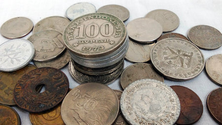 Antique coin collection, featuring a stack of 100 Rupiah coins from Indonesia dated 1973.