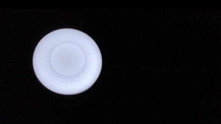 The bright circular ceiling lights against the deep black backdrop create a striking minimalist...
