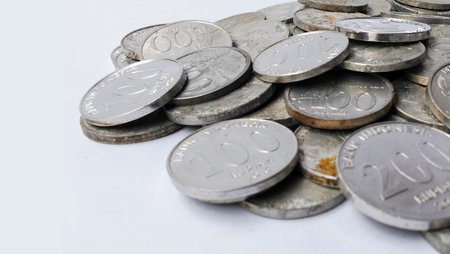 Various Indonesian Rupiah coins are scattered on a white background.