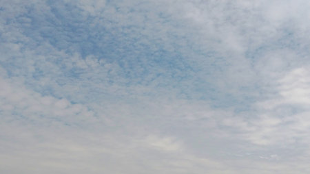 A calm sky with scattered thin clouds, with patches of blue visible among them.の写真素材