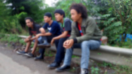 A group of friends sitting outside on the side of the roadの写真素材