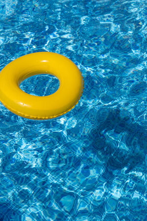 Yellow pool float, pool ring in cool blue refreshing swimming poolの写真素材
