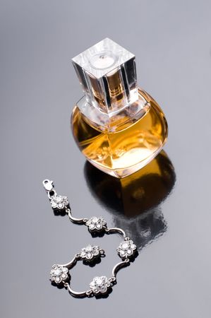 Perfume for women and silver bracelet on gray
