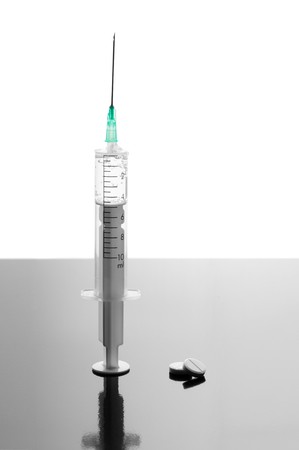 Syringe and tablets on black glossy backgroundの写真素材