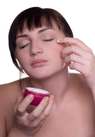 Beautiful woman applying creme on faceの写真素材