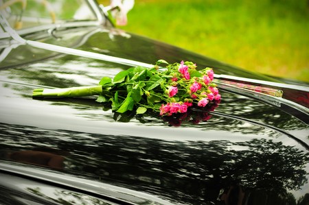 Pink wedding bouquet on cowl of  black carの写真素材