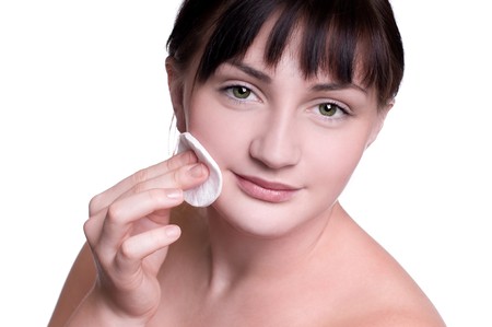 young woman using a cotton pad to remove her make-upの写真素材