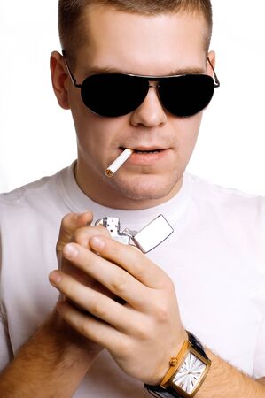 sexy strong man in sunglasses lighting his cigarette isolated on whiteの写真素材