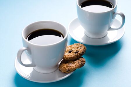 Two coffee cups with cookies on blue backgroundの写真素材