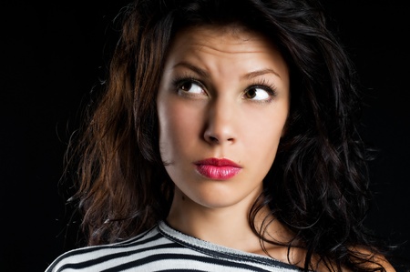 Young beautiful girl looking at copyspace having a surprised or satisfied look isolated on blackの写真素材