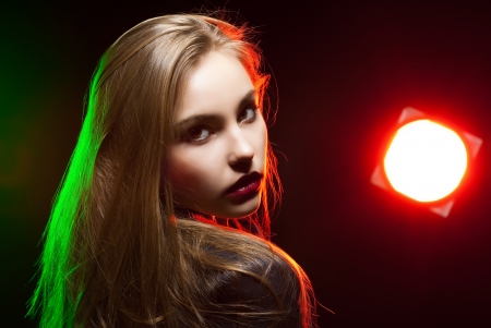 Beautiful girl posing in front of shining colored creative lighting backgroundの写真素材