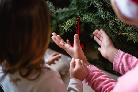 Children hands decorating Christmas tree at homeの写真素材