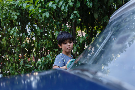Girl with short black haircut washing blue car in the gardenの写真素材