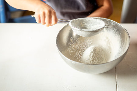 a close view of the hand of the child sifting flourの写真素材