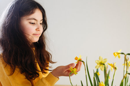 waist up portrait of dark haired girl touching daffodil flowersの写真素材