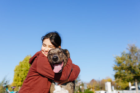 Girl with dark hairs hugs her grey dogの写真素材