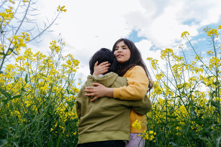 two girls hugging each other in the field with yellow flowersの写真素材