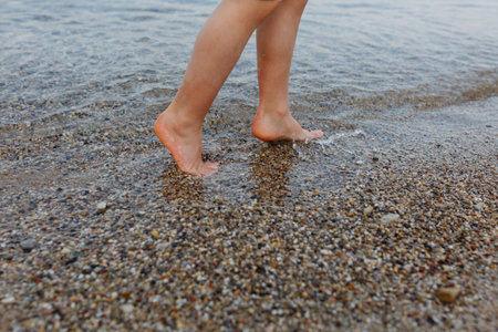 barefeet child legs walking on stone beach