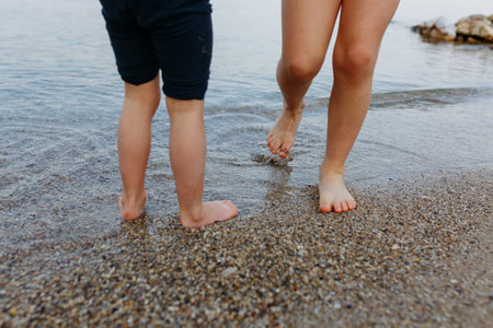 barefeet of two children walking on the beach at the lakeの写真素材
