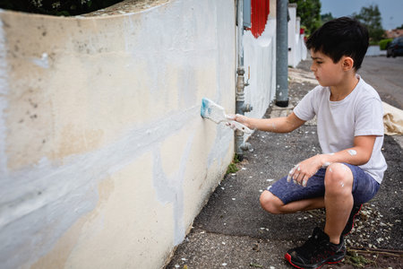 side view on sitting girl painting with brush house fenceの写真素材