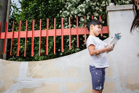 low angle view on standing girl painting with brush house fenceの写真素材