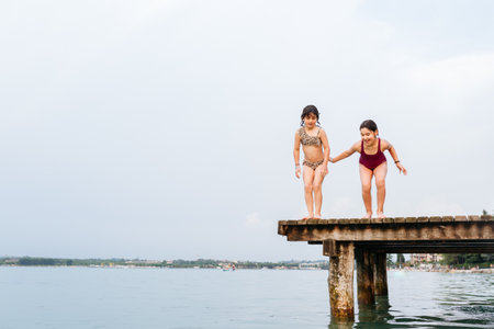 two children jumping from the bridge in the waterの写真素材