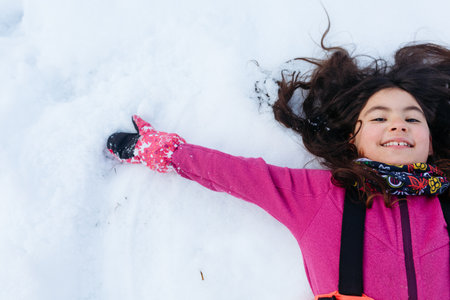 close up portrait of smiling girl with dark hair lying on the snowの写真素材