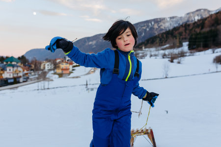 girl with short dark hair pulling up the wooden sled in snowy mountainの写真素材