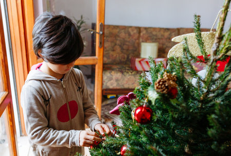 high angle view on child in rudolf overall decorating christmas treeの写真素材