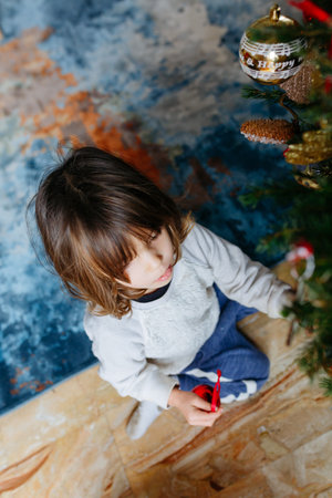 high angle view on small sitting child busy decorating christmas tree at home