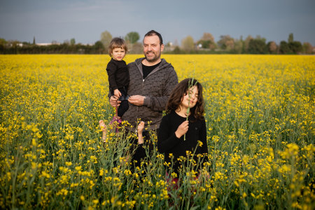 smiling family of three kids and a father standing amidst yellow flowers