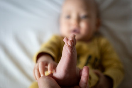 upper view on a lying baby bare foot held my parent handの写真素材