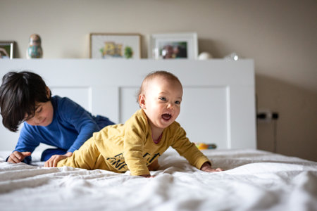 two happy children playing with each other in the parents bedroomの写真素材