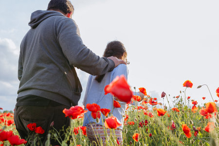 rear view of father and daughter walking away in the poppy field on a sunny dayの写真素材