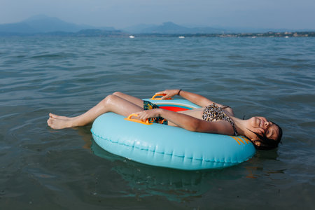 happy girl with short dark hair relaxing lying down on top of the inflatable ring